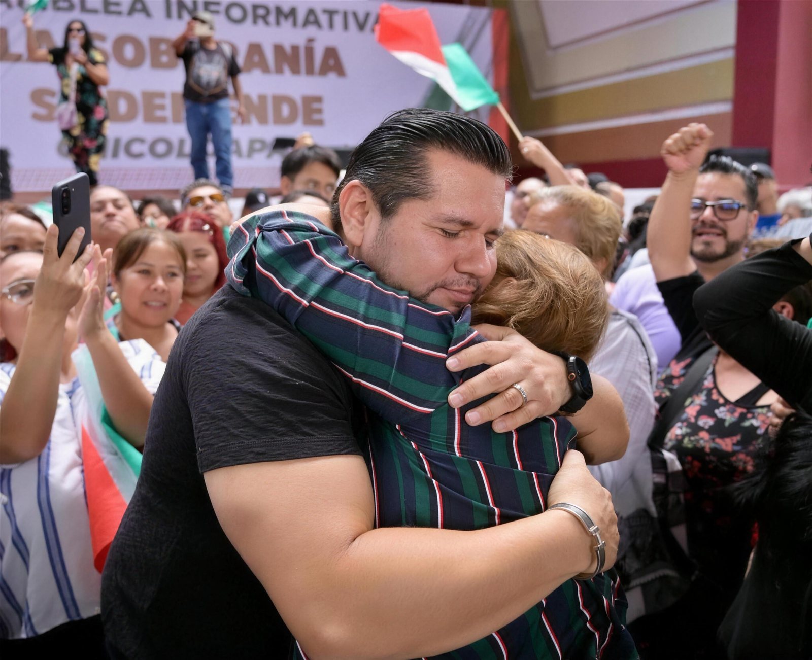 Samuel Ríos abrazando a una vecina durante una asamblea informativa